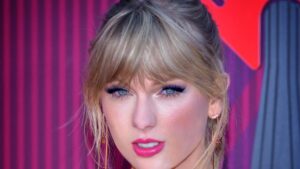 Taylor Swift aux iHeartRadio Music Awards en 2019. Dans la lumière rose du tapis rouge, la chanteuse pose face aux photographes. Crédits : Glenn Francis / PacificProDigital.com, CC BY-SA 4.0.
